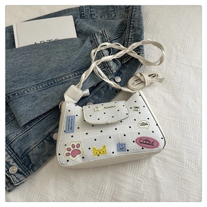 Close-up of white leather tote bag featuring black polka dots and cute cartoon cat patches