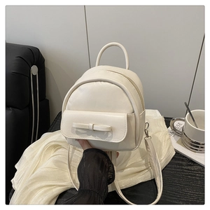 Close-up of cream mini backpack featuring a stylish bow and smooth leather texture