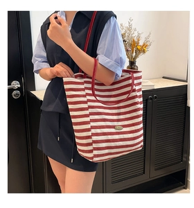 Detail of red and white striped canvas tote bag with shoulder strap on a model