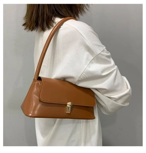 Gros plan d'un sac baguette en cuir PU marron avec boucle dorée sur un t-shirt blanc
