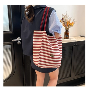 Detailed close-up of red and white striped canvas tote bag with slim red shoulder straps