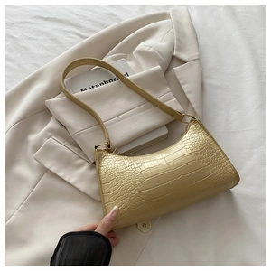 Macro detail of champagne gold crocodile pattern leather on crescent underarm bag