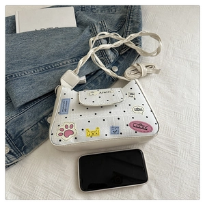 Close-up of white woven bag with black polka dots and cute cartoon embroidery patches