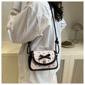 Détail du sac bandoulière rose à imprimé papillons avec pendentif cœur et nœuds noirs