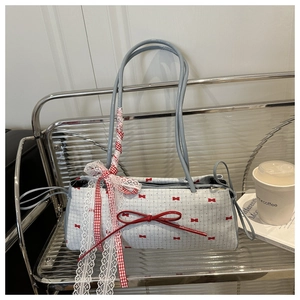 Détail du sac à main à carreaux bleu clair avec nœuds rouges et ruban dentelle sur socle