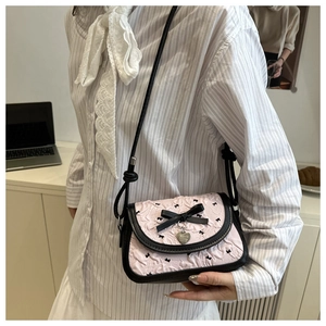 Détail du sac à fleurs rose avec nœud en soie et pendentif cœur sur un mannequin