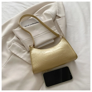 Detail of pale gold faux crocodile leather underarm bag showing size compared to a smartphone