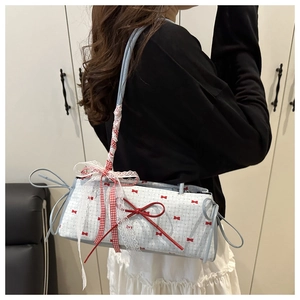 Detail of light blue crossbody bag with red bow patterns, lace trim, and ribbon strap