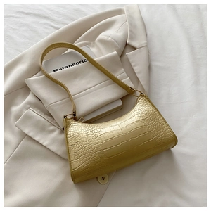 Detail showing high-gloss crocodile embossed texture on mustard green baguette bag