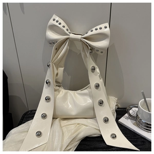 Detail of cream white PU handbag featuring large bow handle and silver rivet decorations