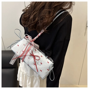 Detail of light blue lace shoulder bag with red bows and checkered ribbon strap