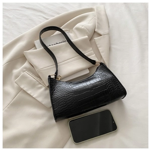 Close-up of black crocodile-embossed baguette bag with elegant gold metal hardware detail