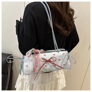 Detail of sweet blue shoulder bag with lace trim, red bow print and ribbon drawstring