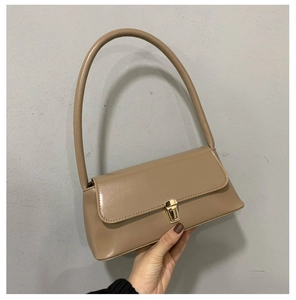 Gros plan sur le sac sous le bras café clair minimaliste avec boucle dorée élégante