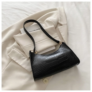 Detailed view of black crocodile pattern leather underarm bag with gold metal buckle