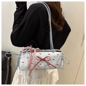 Detail of light blue shoulder bag featuring red bow prints and white lace ribbon decoration