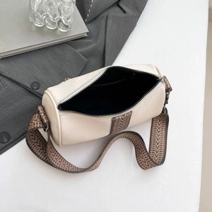 Vintage beige cylinder crossbody bag with wide shoulder strap and textured leather finish