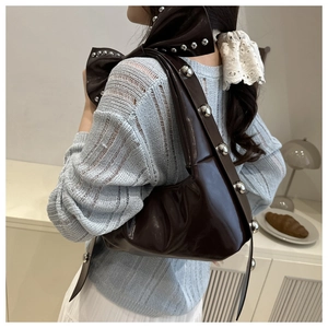 Detail of dark brown glossy patent leather shoulder bag with silver ball rivet studs
