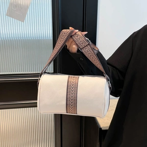 White barrel bag with ethnic woven strap and lychee grain leather texture held by model