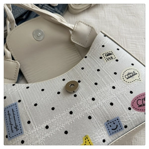 Close-up of white polka dot tote bag featuring colorful embroidery and magnetic clasp