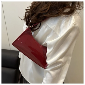 Close-up of shiny red patent leather shoulder bag worn by model in white shirt