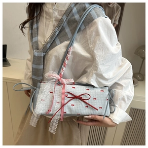Détail d'un sac bleu clair avec nœud rouge, dentelle blanche et motifs vintage coquette