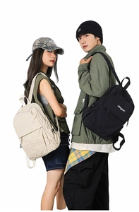 Detail of couple backpacks in cream and black colors showing Songuo embroidery and nylon texture