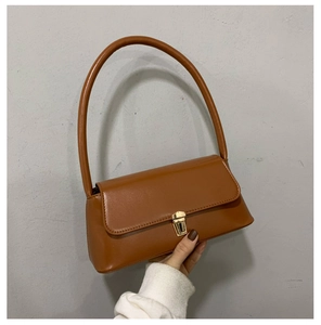 Détail de la texture en similicuir marron caramel et boucle dorée du sac baguette