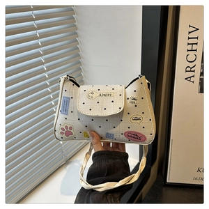Detail shot of a cream square bag with black polka dots and cute cartoon patches