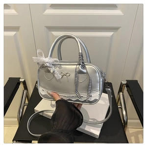 Detail of silver balletcore Boston bag with lace trim and decorative bows on top