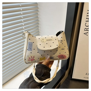 Detail of white woven tote bag featuring black polka dots and artistic cat patches