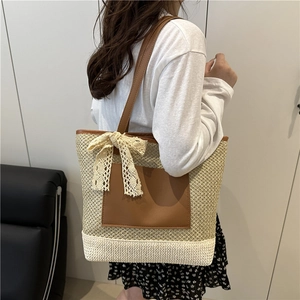 Woven straw tote bag with brown leather handles and lace bow for summer beach vacation