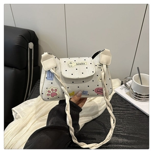 Close-up of cream polka dot tote bag with cartoon patches and woven strap detail