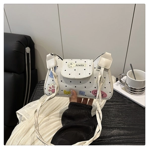 Detail of white polka dot tote bag with colorful cartoon patches and braided shoulder strap