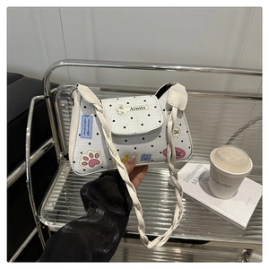 Detail of white polka dot tote bag with colorful cartoon patches and white braided strap