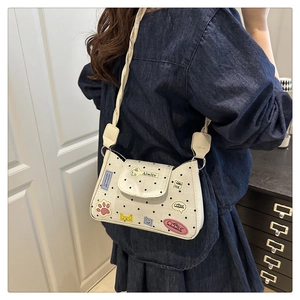 Detailed view of white polka dot bag with colorful cartoon stickers and braided strap