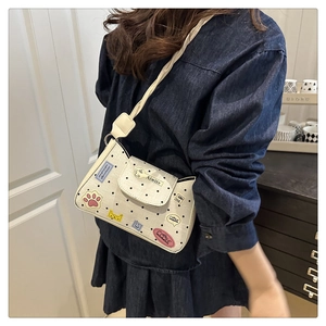 Detailed view of a white polka dot crossbody bag with cute cartoon patches on a model