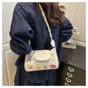 Detailed view of white polka dot shoulder bag with cute cartoon patches and woven strap