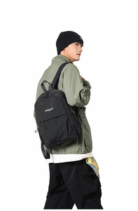 Close-up of black waterproof nylon backpack featuring a flap pocket and side drawstring details