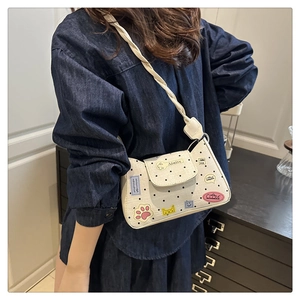 Detail of cream polka dot shoulder bag with cute cartoon patches and braided strap design