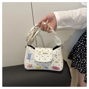 Detail of white canvas tote bag with black polka dots, cartoon patches, and rope handles