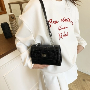 Glossy black crocodile pattern crossbody bag with silver chain strap shown with a model
