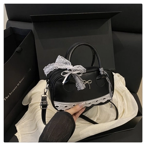 Close-up of black lace Boston bag with delicate bows and ribbon handle detail