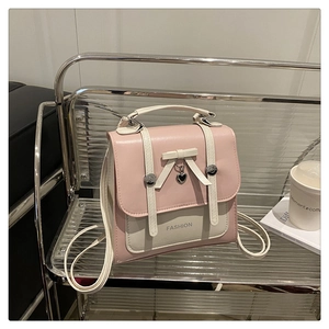 Detailed close-up of pink and white PU leather backpack with bow and heart pendant charm
