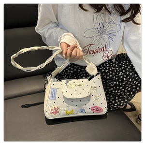 Close-up of white polka dot tote bag featuring colorful cartoon patches and woven handle