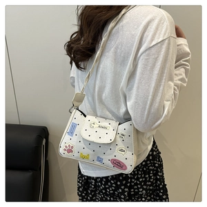 Polka dot white leather tote bag with cute stickers shown worn as a shoulder bag