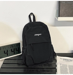 Detail shot of black nylon backpack featuring a front pocket and white songuo logo branding