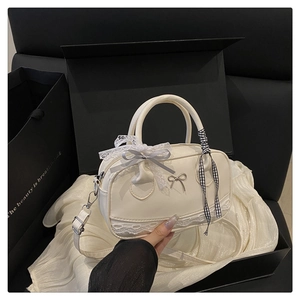 Close-up of cream lace Boston bag with silver bow detail and check ribbon charm