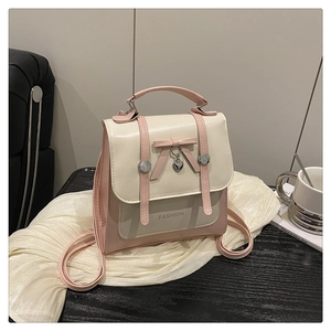 Detail of pink and white bow backpack with heart pendant and Fashion text on leather surface