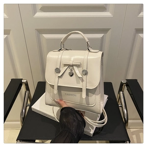 Detail of cream vintage backpack with bow pendant and Fashion text on a chair